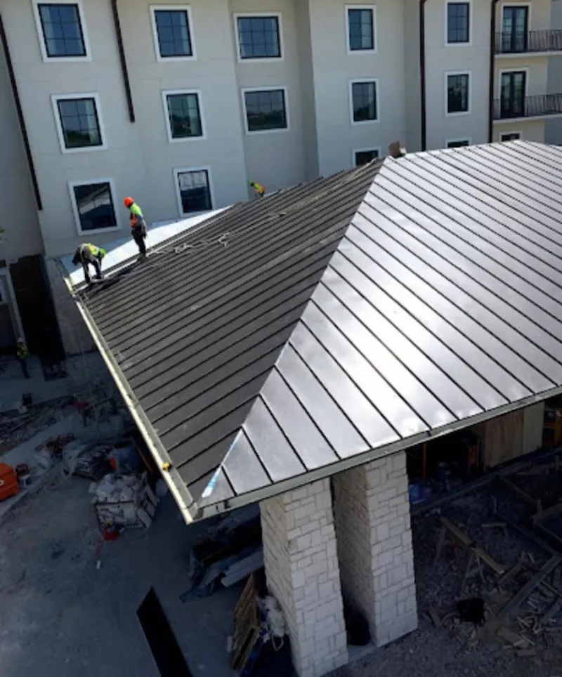 Crew installing standing seam metal roof panels on a commercial project in Odenville